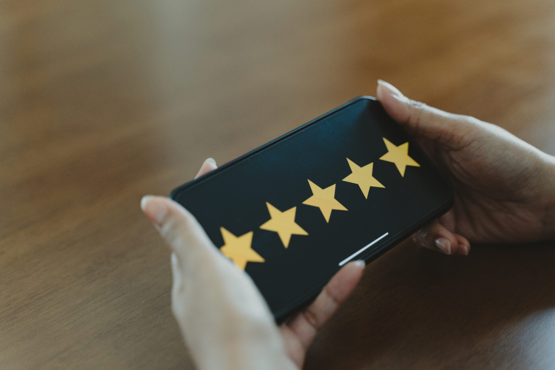 Hands are holding a smartphone with five stars on the screen, demonstrating good online reputation management.
