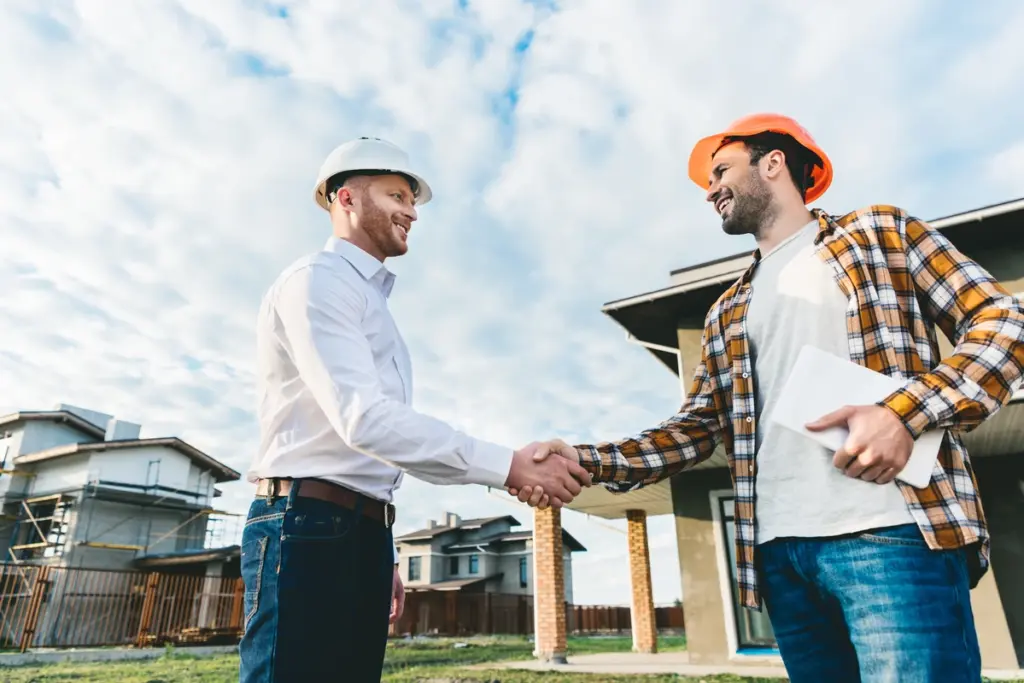 Home Service Business Marketing - Two men shaking hands in front of a nice home after finishing a project.